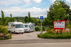 Zwei Wohnmobile auf einem Wohnmobilstellplatz im Grünen.