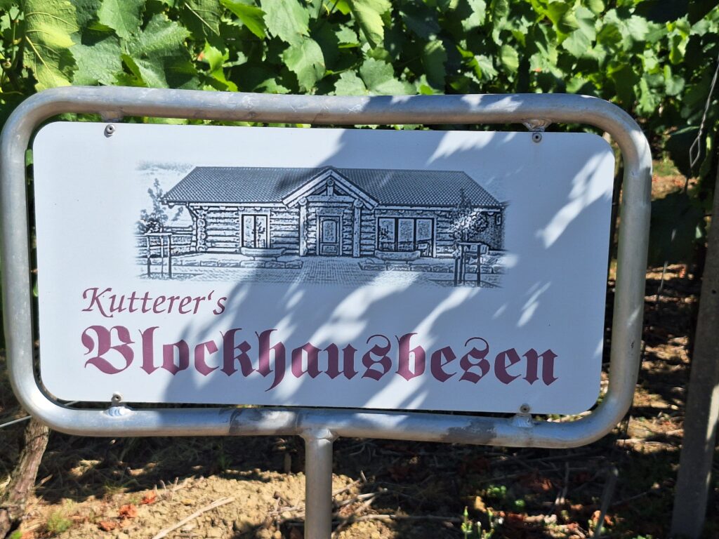 Nahaufnahme eines Schilds mit dem Schriftzug "Kutterer's Blockhausbesen" und der Abbildung eines Blockhauses.